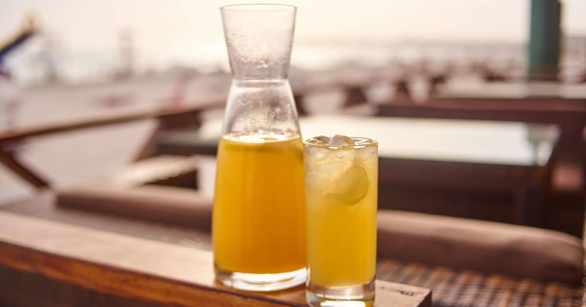 gin and juice drink pictured with a carafe of orange juice on a bar top