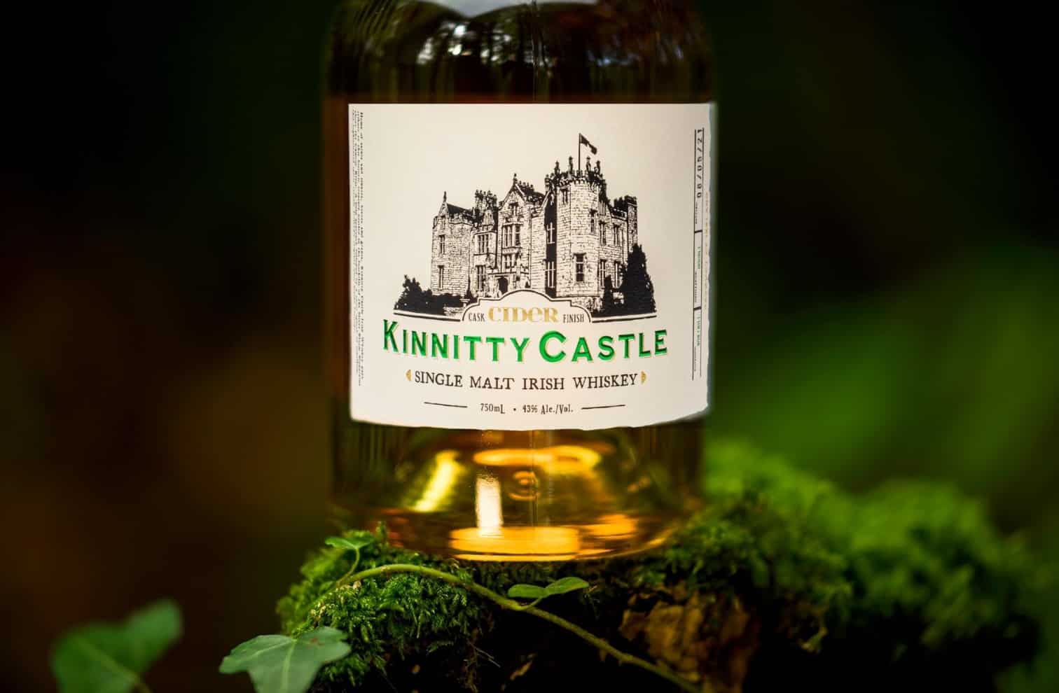 A bottle of Kinnitty Castle Irish Whiskey Aged 10 Years next to a bottle of Kinnitty Castle IRish Whiskey Dapper Blend on a table with a blurred background